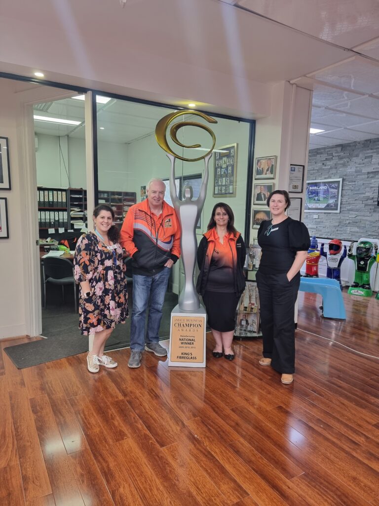 A picture of a group of people at a business in front of some of their fibreglass products